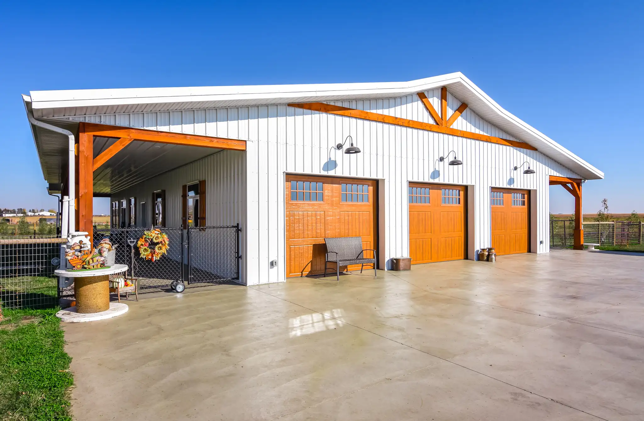 Wood-tone doors and accents on a barndominium with a 3 car garage