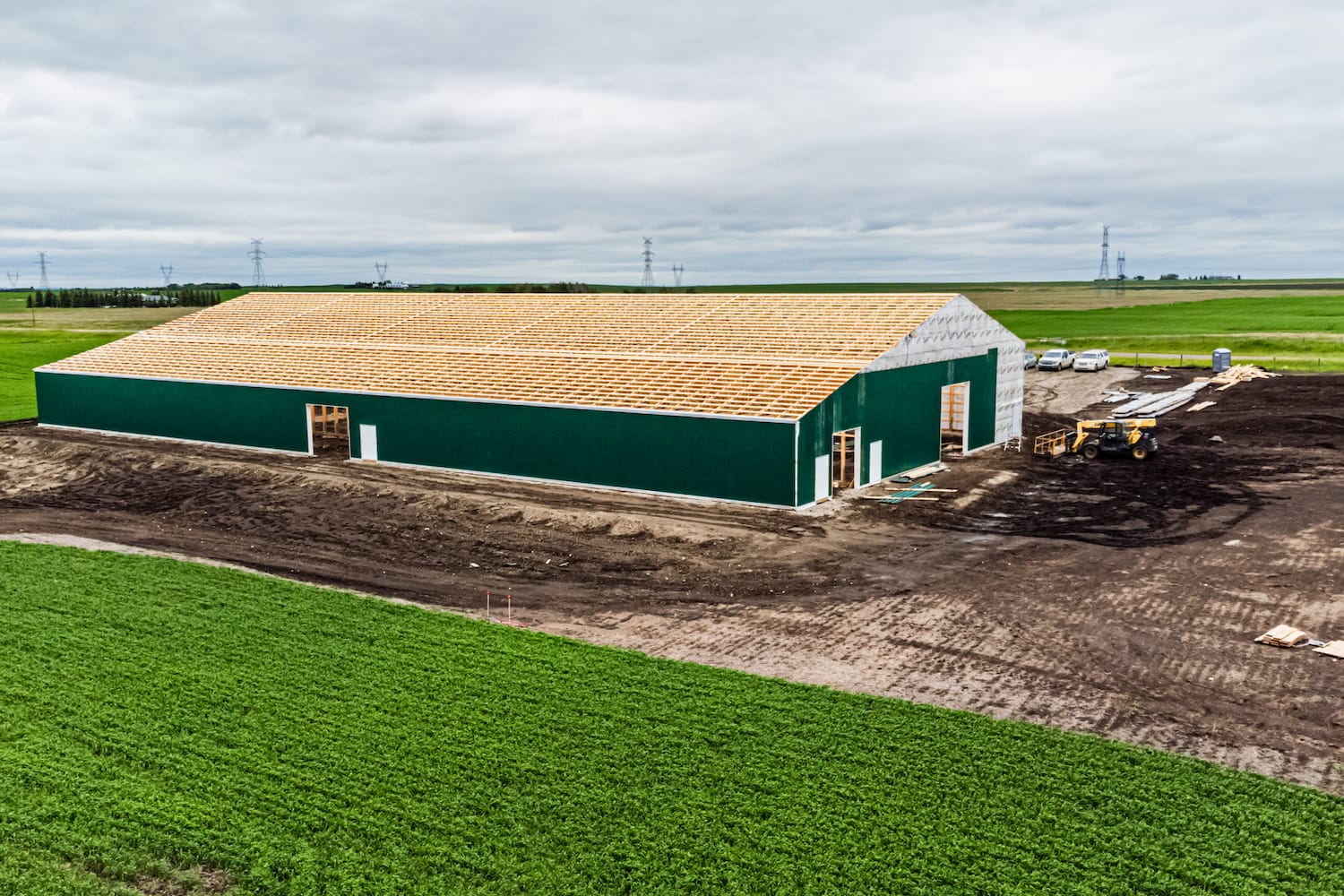 A large, modern post frame building under construction. The scale outlines the difference between post frame vs pole barn