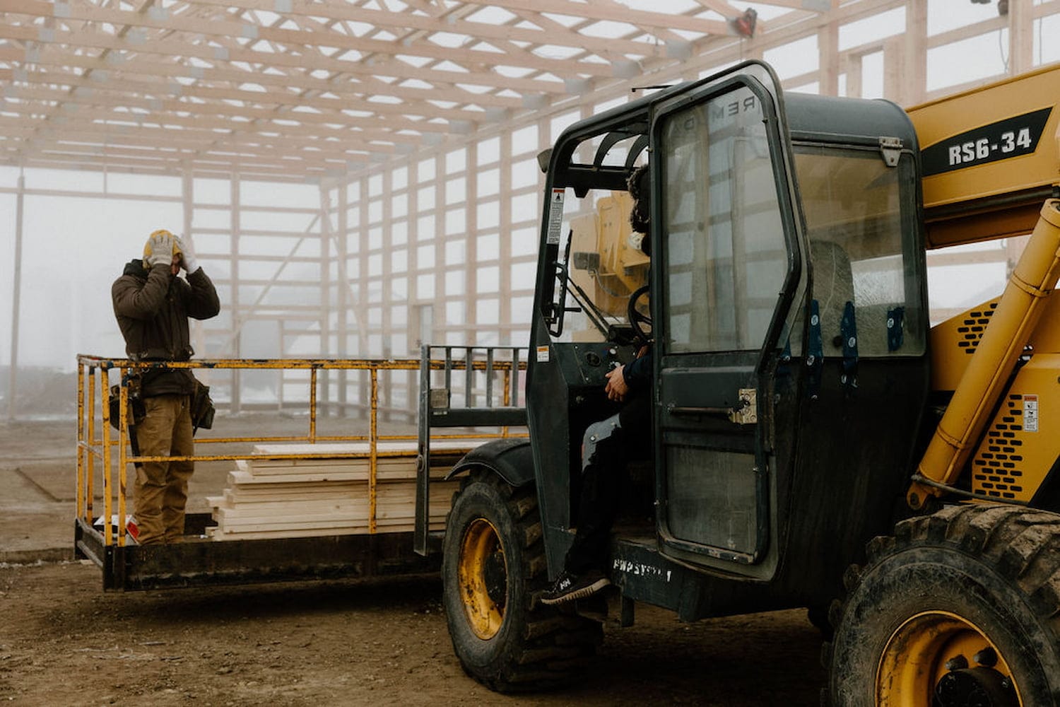 Post frame construction crew and equipment making a large post frame building
